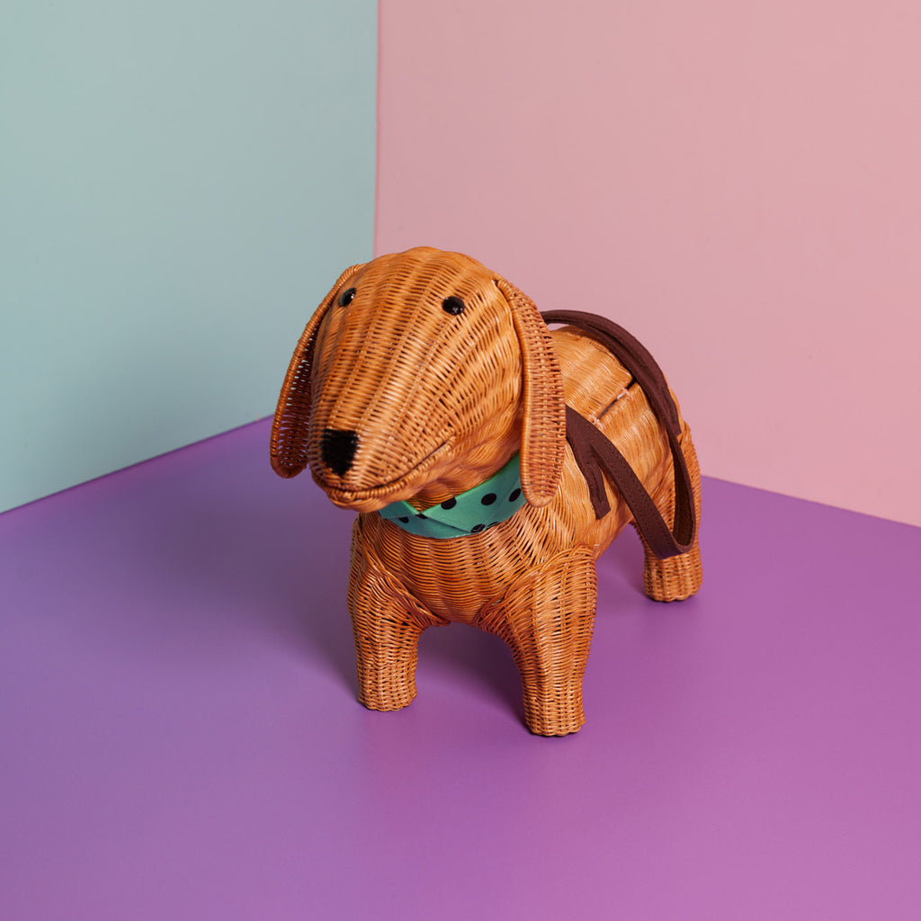 Andouille Sausage dog purse Dachshund handbag wears a blue bow-tie and sits in a colourful background