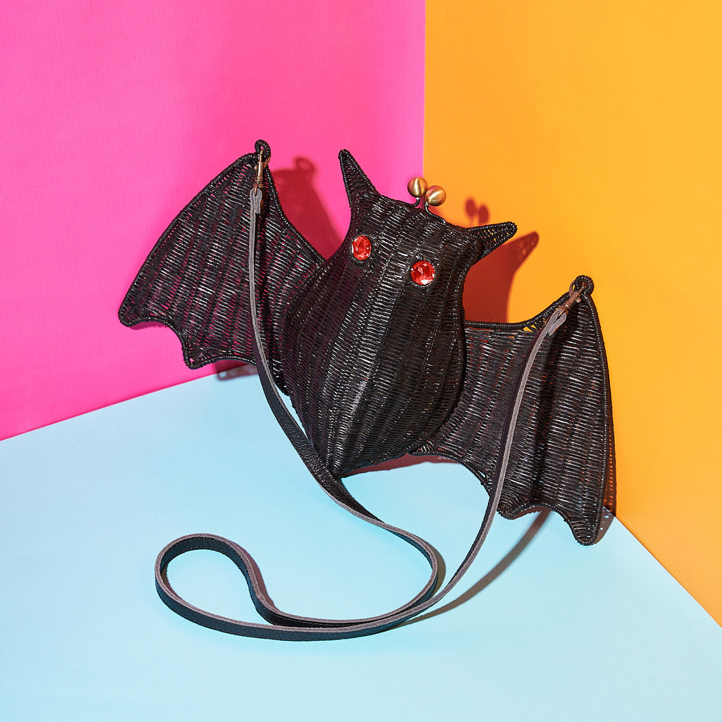 Wicker Darling battie page bat shaped purse red eyed bat sits in a colourful background