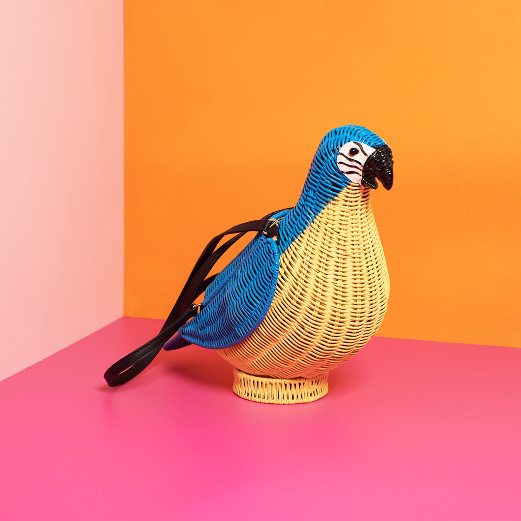 Wicker Darling blue macaw bag macaw purse sits in a colourful background