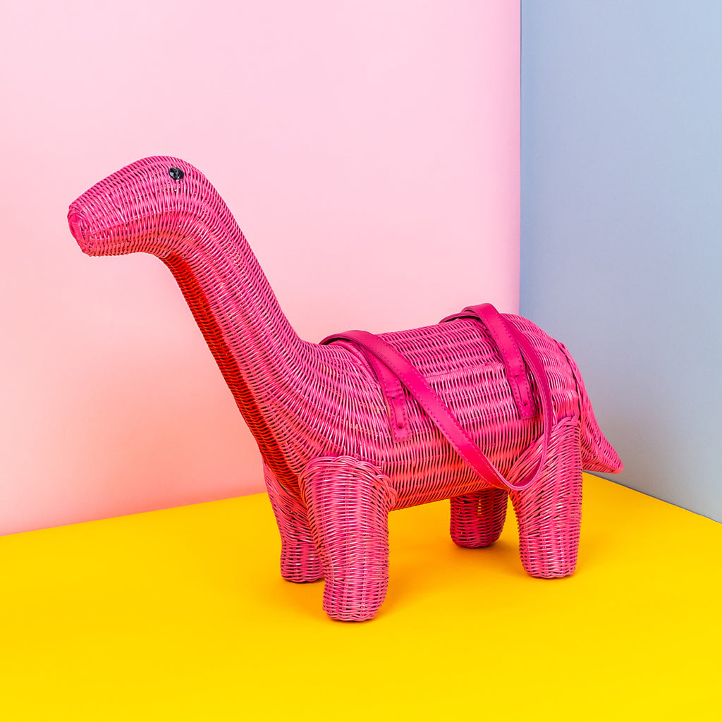 Ann pink brontesaurus dinosaur handbag sits in a colourful bag