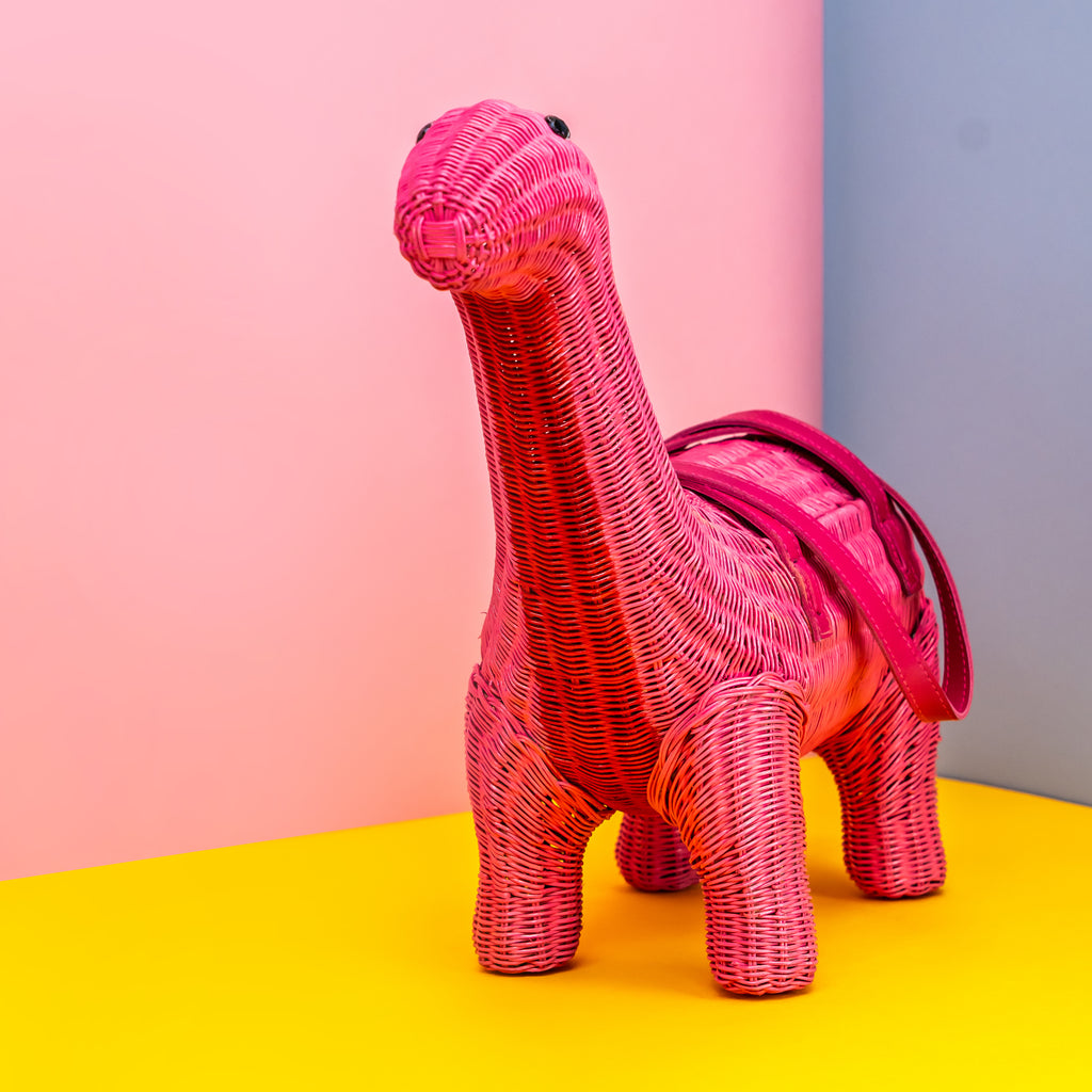 Ann pink brontesaurus dinosaur handbag sits in a colourful bag