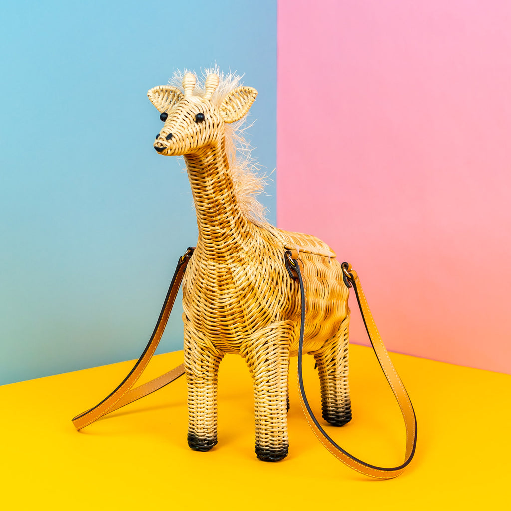 A wicker darling handbag in the shape of a giraffe purse sits in a colourful background.
