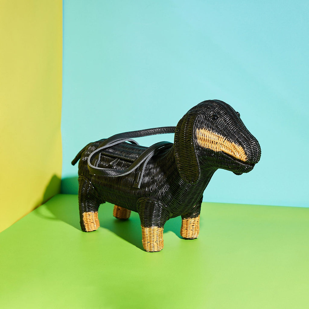 Frank the sausage dog shaped purse from Wicker Darling sits in a colourful background