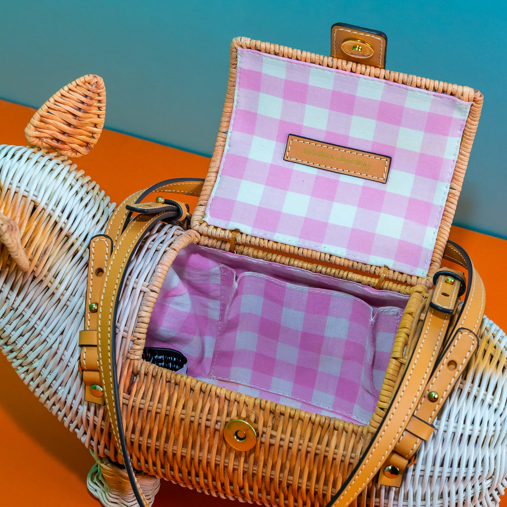 An internal view of the rattan corgi bag. It features a pink gingham lining with an internal pocket.