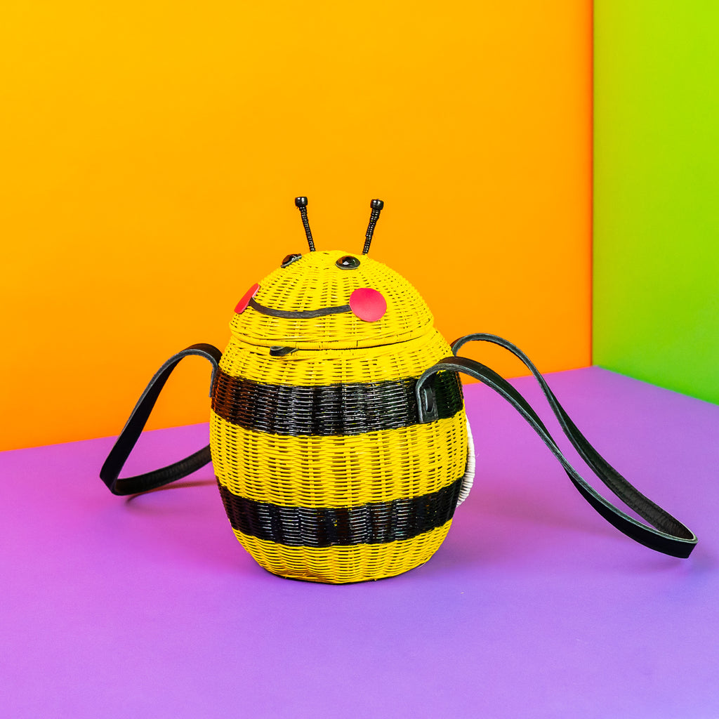 Wicker Darling Beeatrice the Bee purse bee handbag sits in a very colourful room.