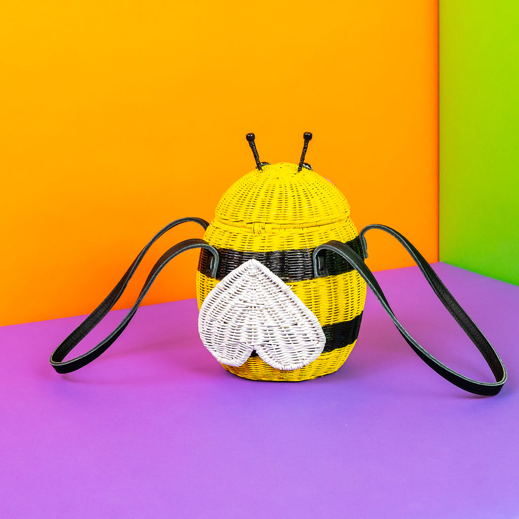 Wicker Darling Beeatrice the Bee purse bee handbag sits in a very colourful room.