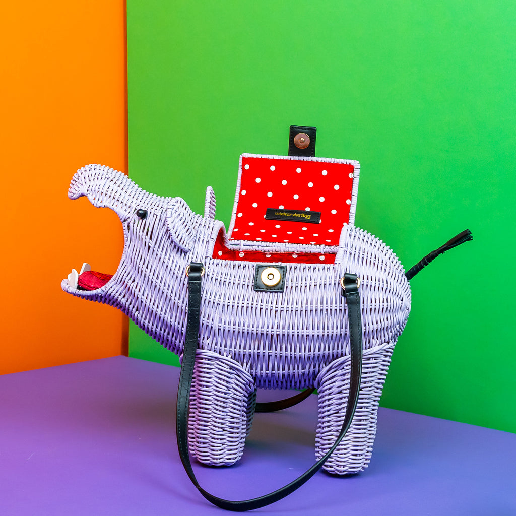 Wicker Darling Hestia the hippo shaped bag sits in a colourful background.