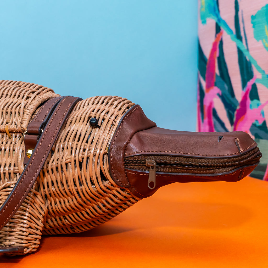 Wicker Darling Platypurse II platypus bag design wicker handbag sits in a colourful background.