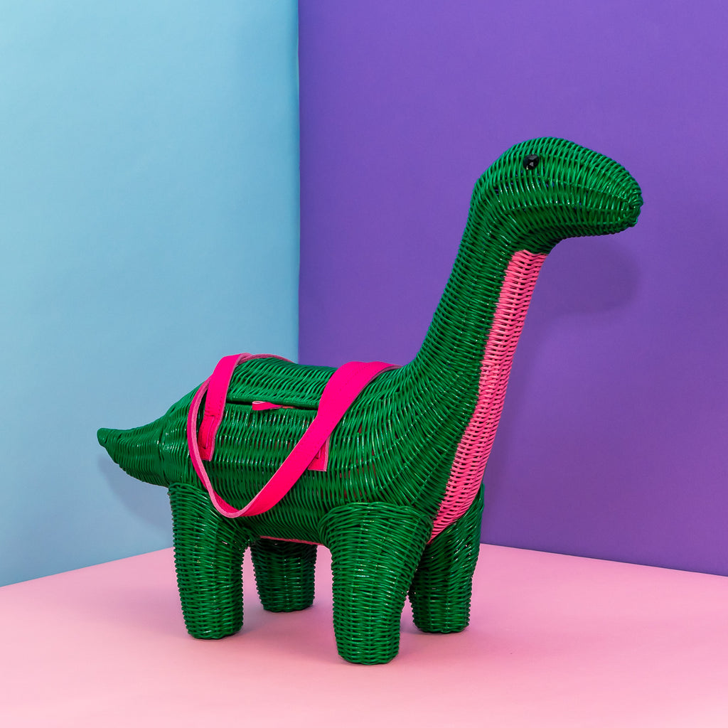 Wicker Darling green dinosaur purse patrick the bront-saurus stands in a colourful background.