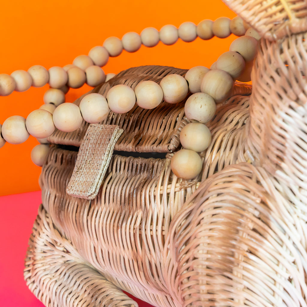 Wicker Darling Lope Jackolope purse jackolope handbag features wooden bead detailing and sits in a colourful room.