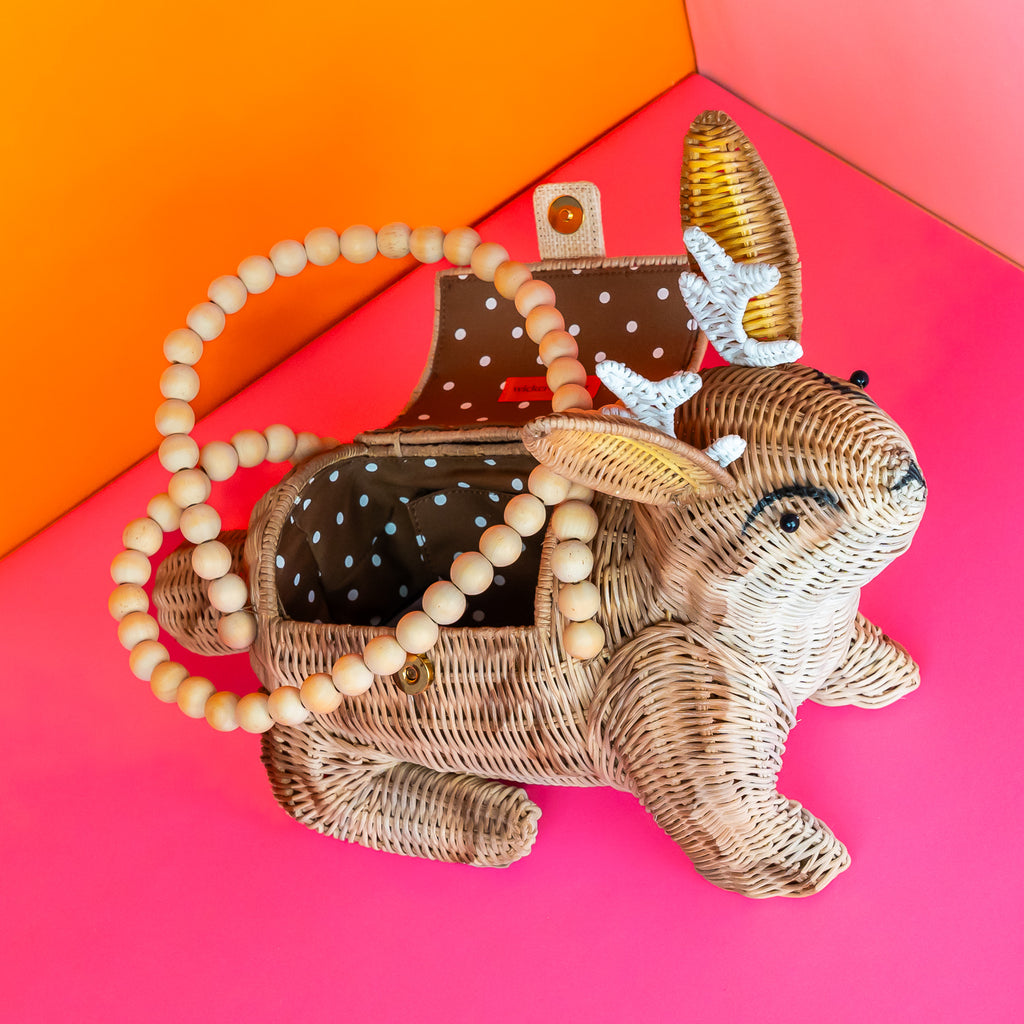 Wicker Darling Lope Jackolope purse jackolope handbag features wooden bead detailing and sits in a colourful room.