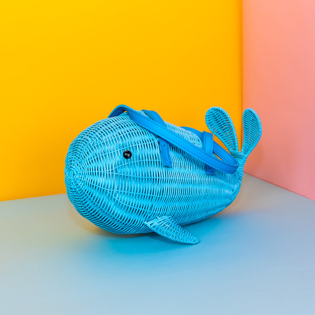 Wicker Darling Squirt whale handbag squirt purse sits in a colourful background.