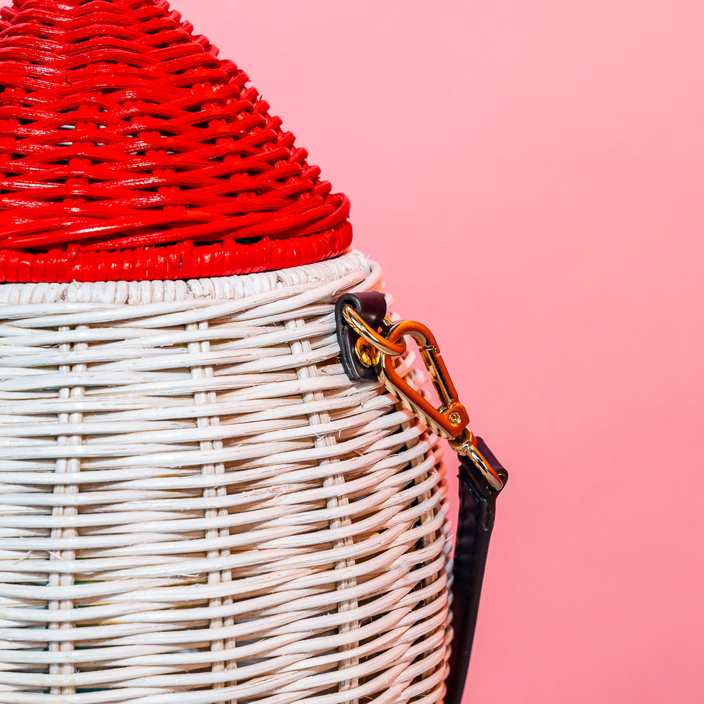 Wicker Darling handmade wicker rocket shaped purse rocket bag sits in a colourful background.