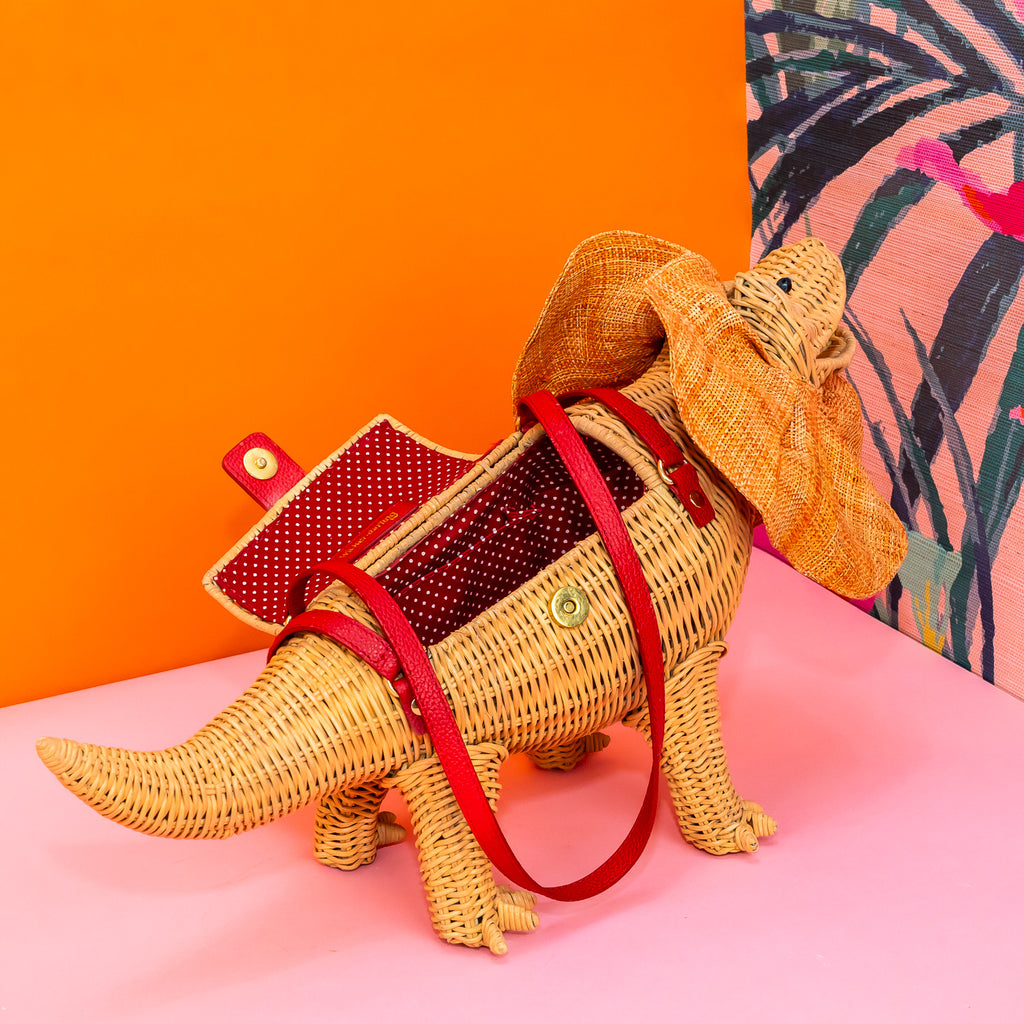 Wicker darling Priscilla Frillneck Wicker Lizard purse lizard handbag sits in a colourful background alongside colourful tropical wallpaper.