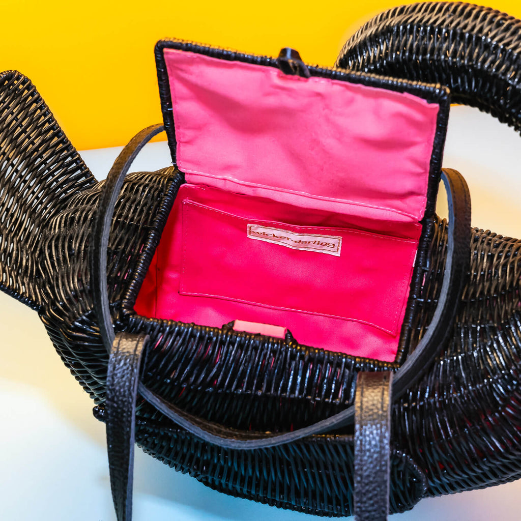 Wicker darling odile black swan purse black swan handbag sits in a colourful yellow and blue background. 