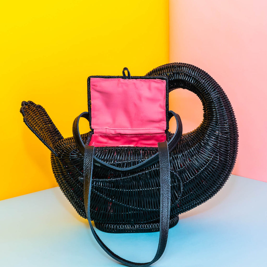 Wicker darling odile black swan purse black swan handbag sits in a colourful yellow and blue background. 