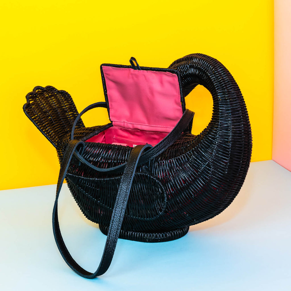 Wicker darling odile black swan purse black swan handbag sits in a colourful yellow and blue background. 