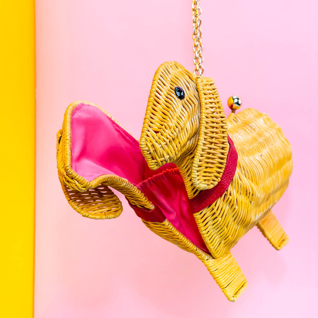 Wicker Darling yellow sausage dog clutch purse sausage dog handbag hands in a colourful room.