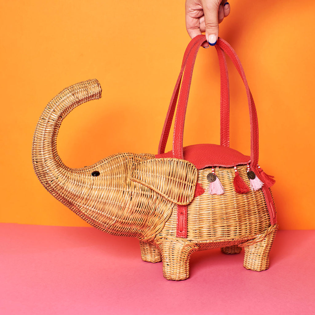 Animal shaped purse elephant shaped bag wicker purse sits in a colourful background