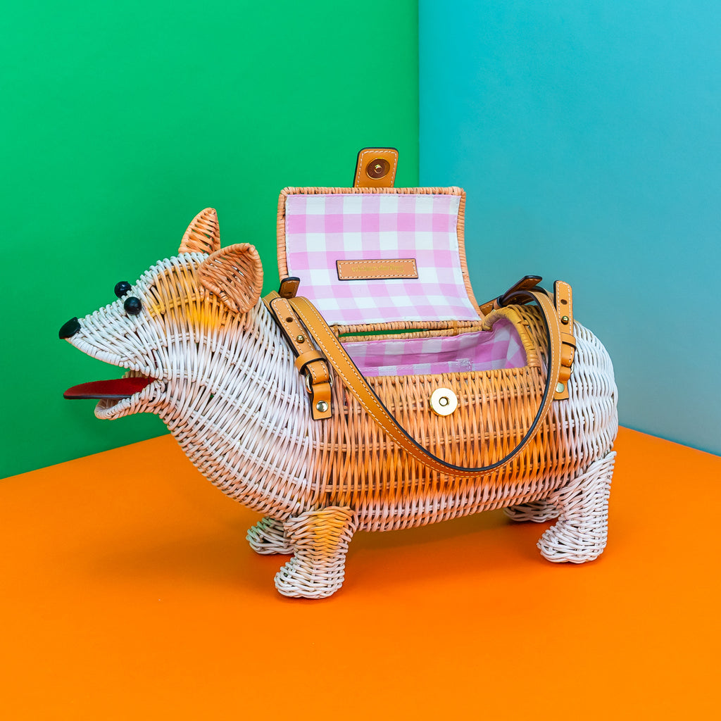 A side view of Cornelius Corgi from Wicker Darling. He has white and tan markings and a pink gingham lining.