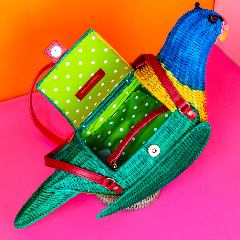 Wicker darling rainbow lorikeet parrot handbag wicker parrot purse sits in a colourful background.