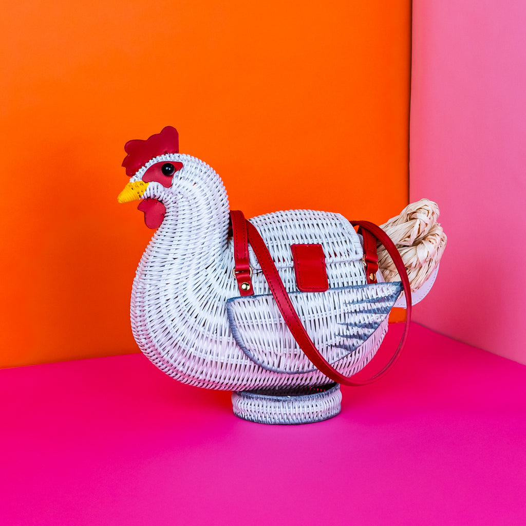 Wicker darling white chicken handbag chicken purse has red detailing and sits in a colourful background.