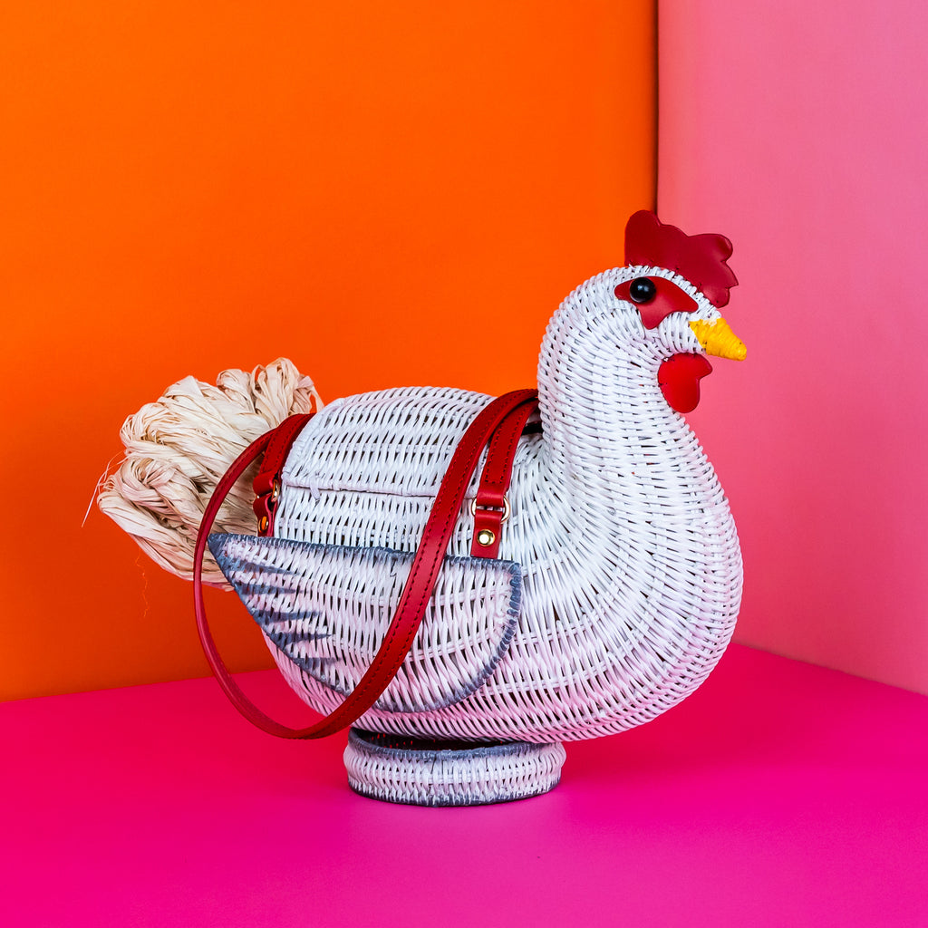 Wicker darling white chicken handbag chicken purse has red detailing and sits in a colourful background.