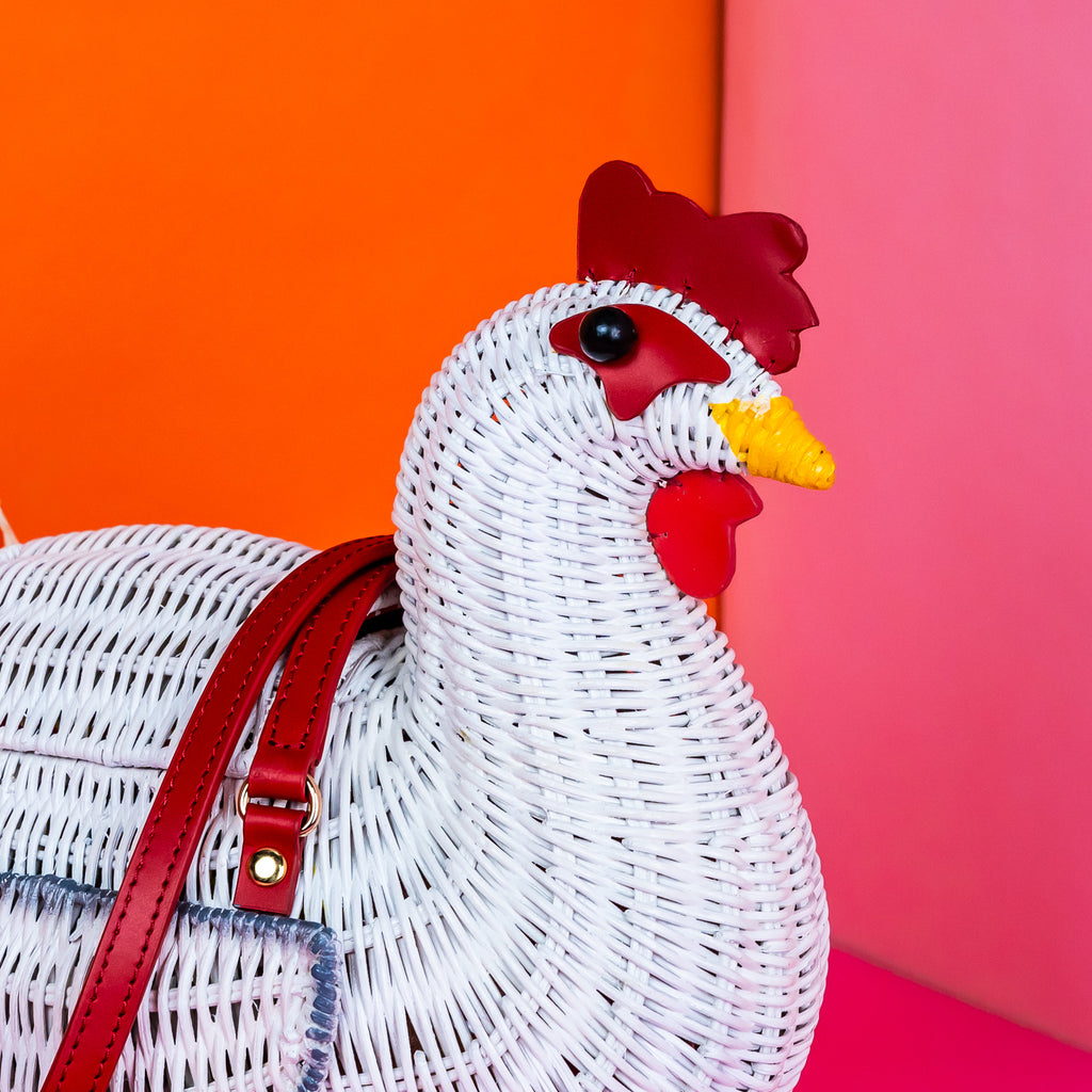 Wicker darling white chicken handbag chicken purse has red detailing and sits in a colourful background.