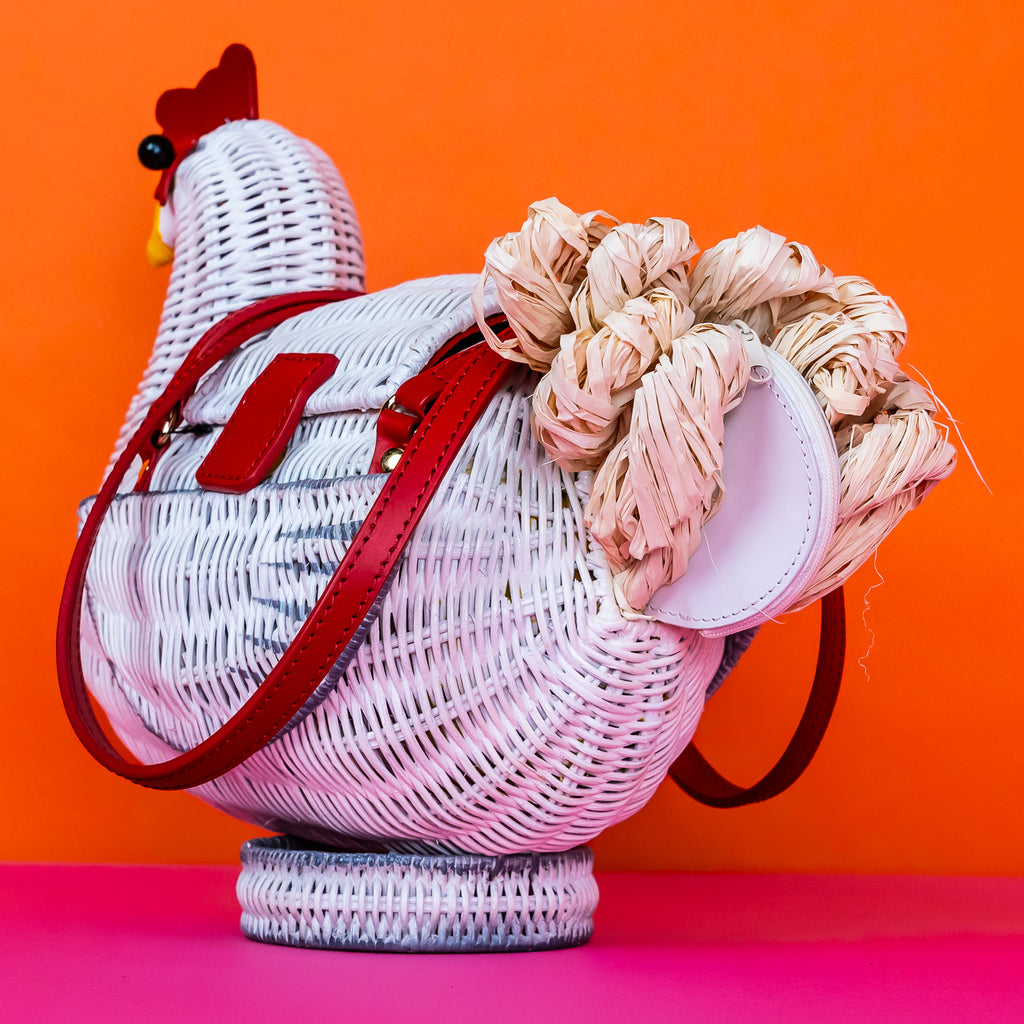 Wicker darling white chicken handbag chicken purse has red detailing and sits in a colourful background.