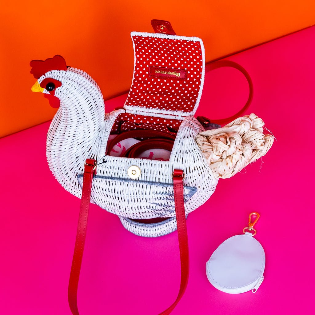 Wicker darling white chicken handbag chicken purse has red detailing and sits in a colourful background.