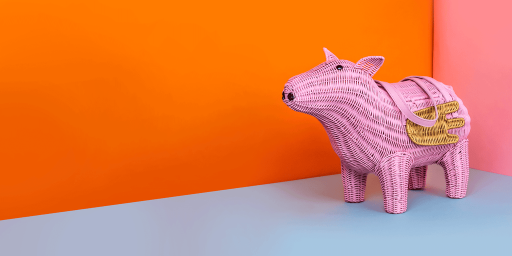 Wicker Darling pigasus pig handbag pink pig purse sits in a colourful room. 