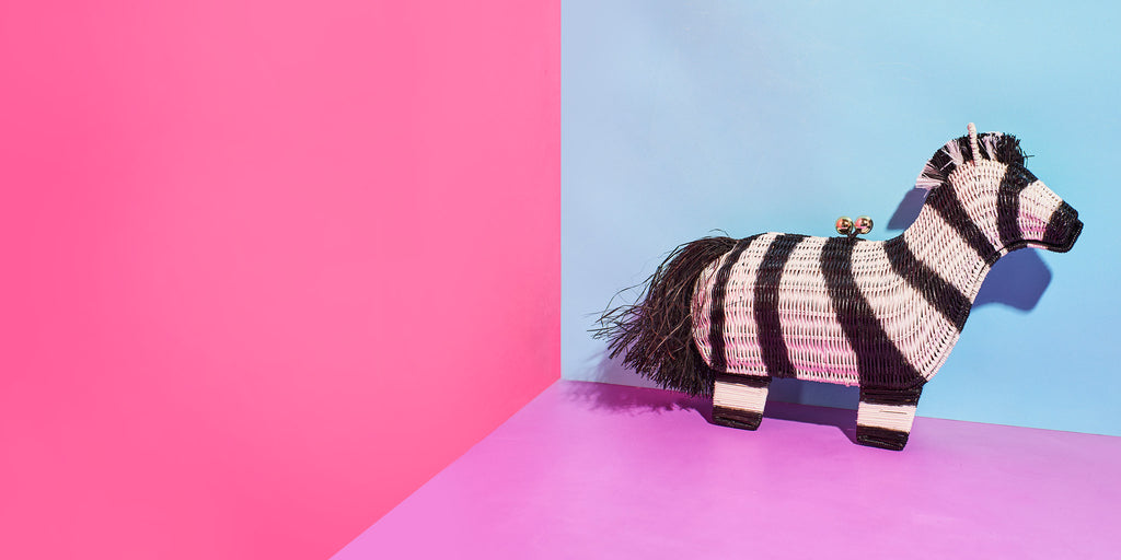 Wicker Darliong's quagga zebra shaped handbag sits in a colourful paper background
