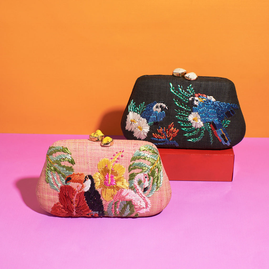 Two Wicker Darling rattan bird clutch purses sit in a colourful background
