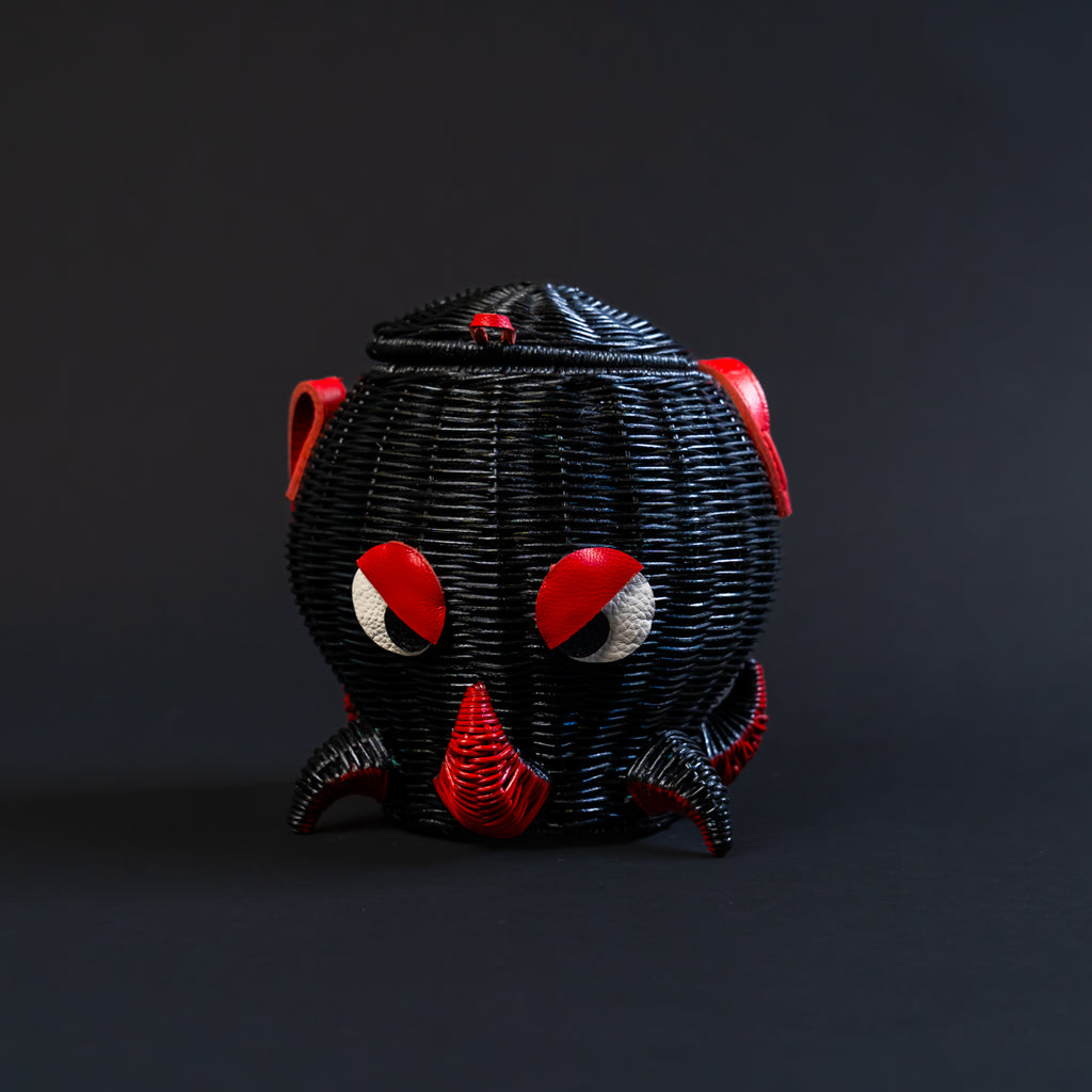 Black woven octopus shaped basket with red and white accents on a dark background. the basket is a handbag.