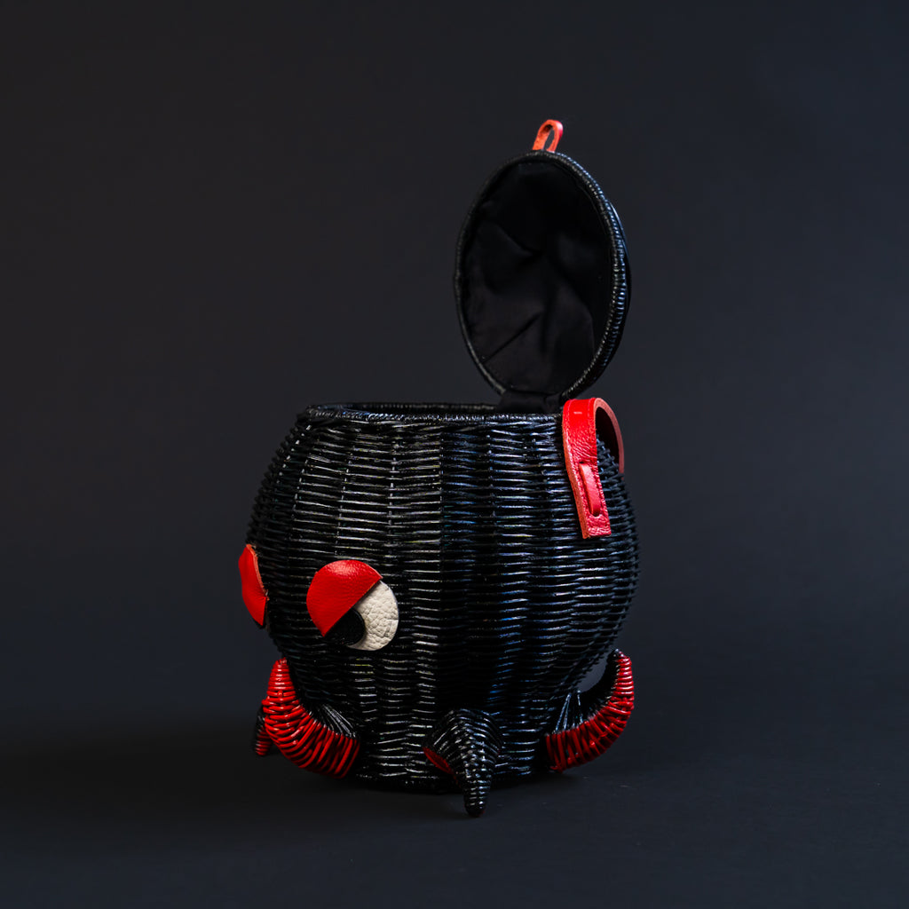 Black woven bag  in an octopus shape with red accents on a black background