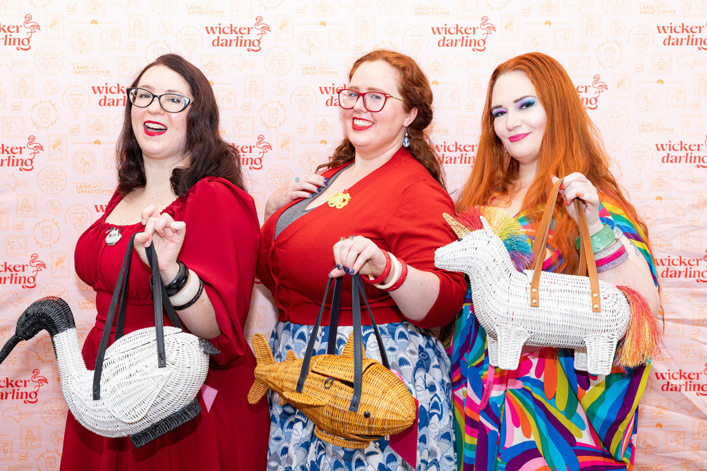 Wicker darling customers stand in a colourful group with their favourite bags- an ibis, a shark and a unicorn wicker bag