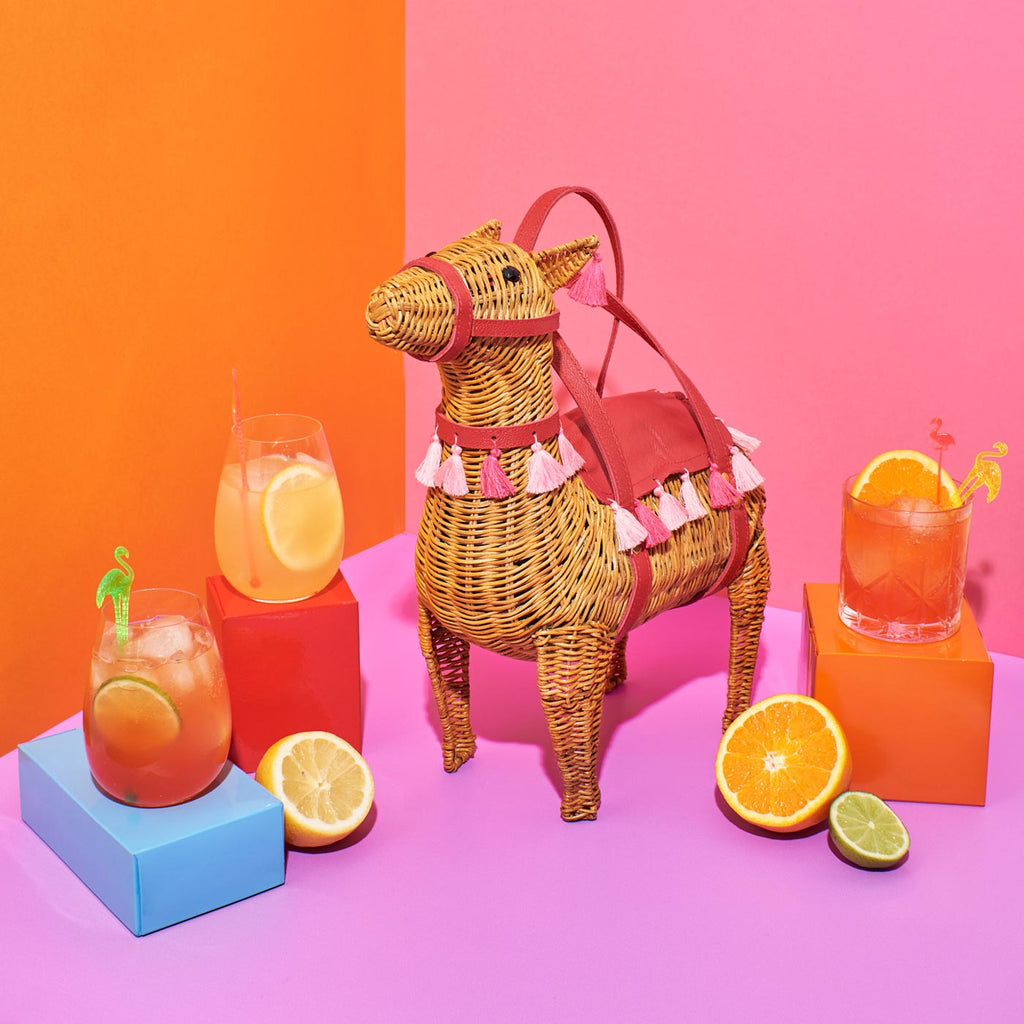 wicker darling lola the llama bag llama wicker bag sits with cocktails in a colourful room, made by Australian designers