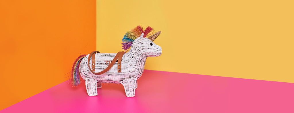 Wicker Darling rainbow unicorn purse unicorn shaped bag sits in a colourful room