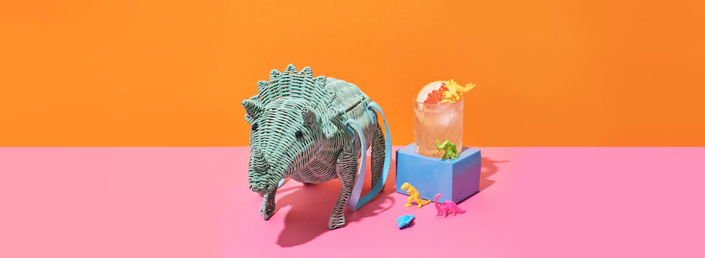 Wicker darling triceratops dinosaur bad with a cocktail in a colourful setting