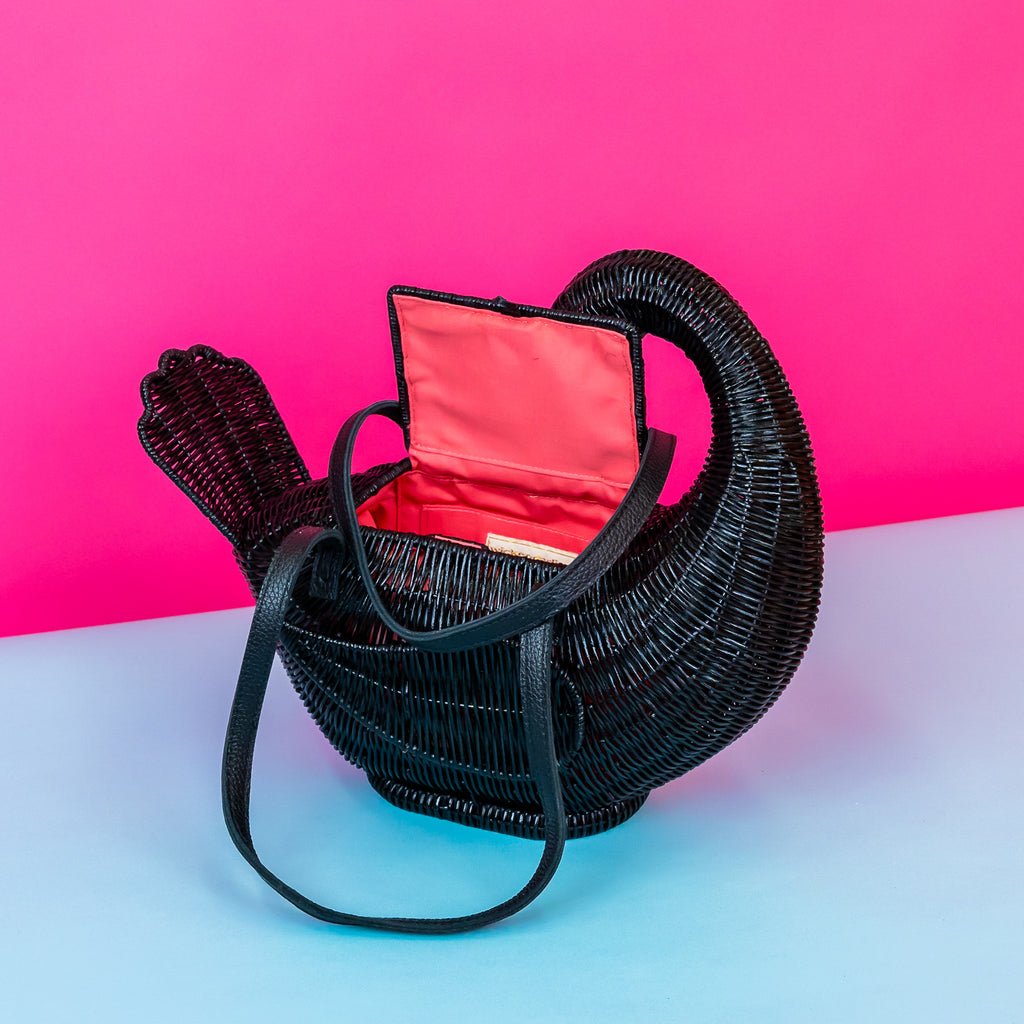 Wicker darling Odile the black swan purse swan handbag sits in a colourful background.