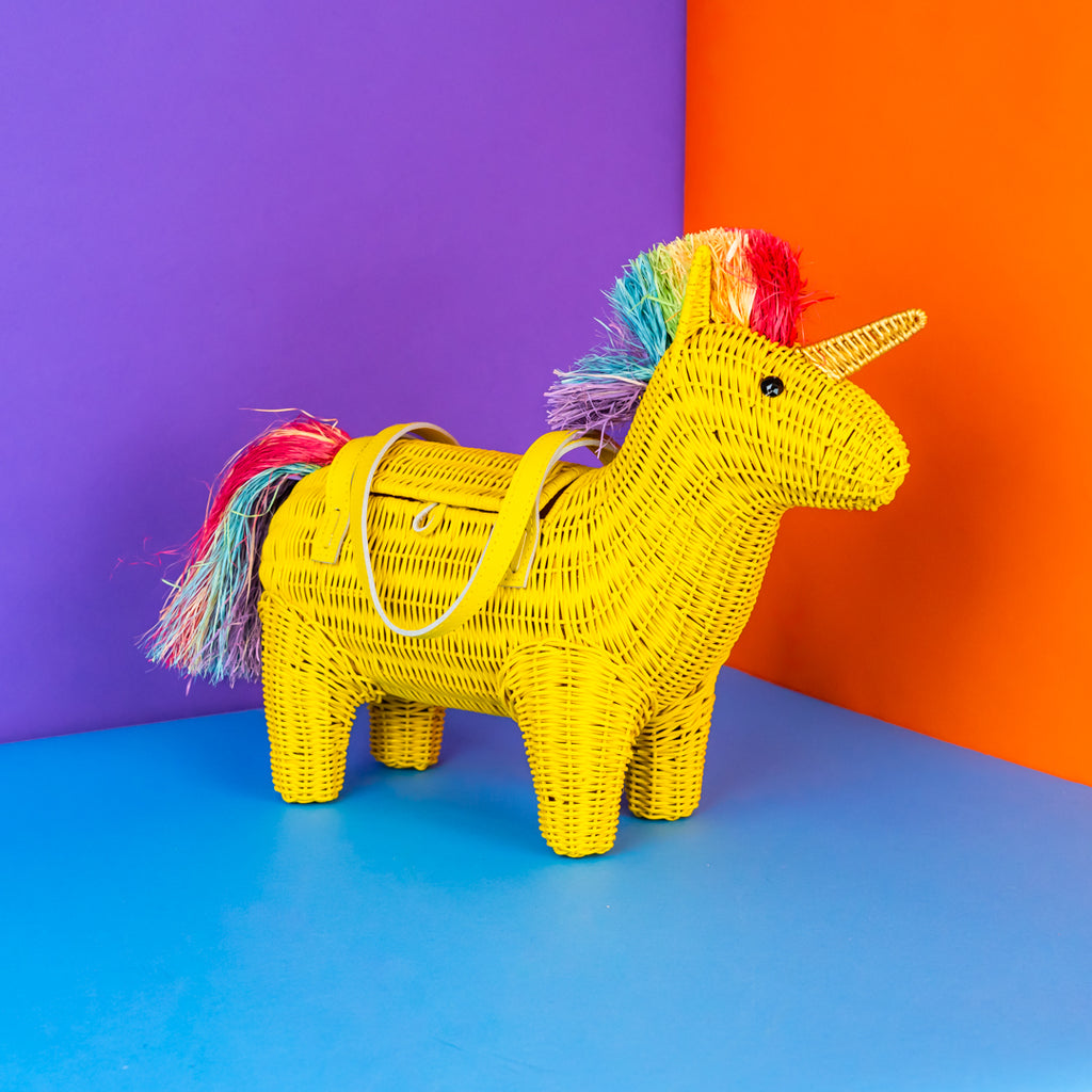 Yellow woven unicorn with a colorful mane on a blue, orange, and purple background