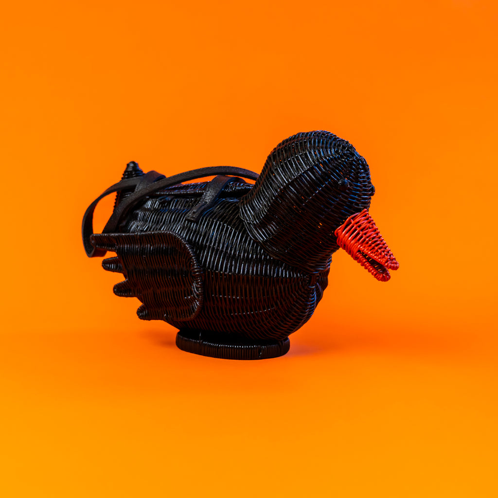 Black bird-shaped object with a red beak on an orange background