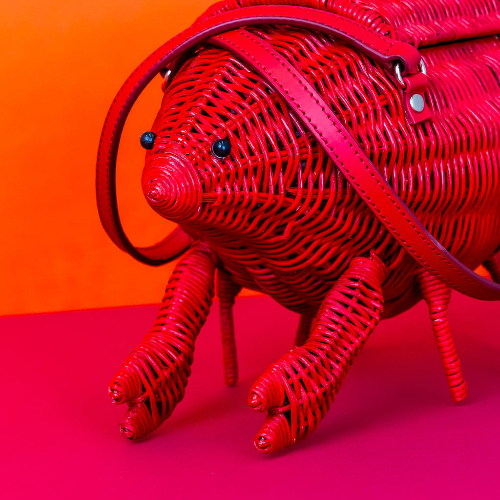 Wicker darling Leonardo Da Pinchy lobster handbag lobster shaped purse sits in a colourful background.