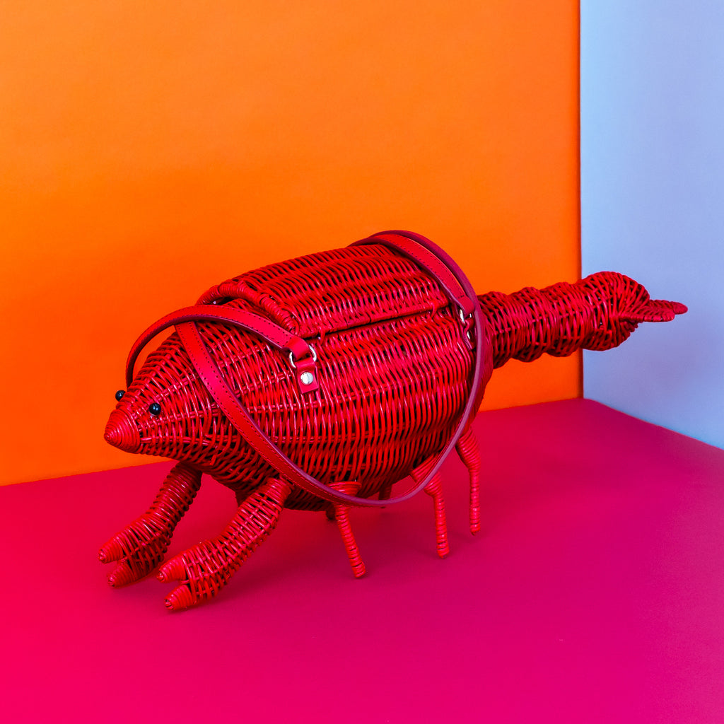 Wicker darling Leonardo Da Pinchy lobster handbag lobster shaped purse sits in a colourful background.