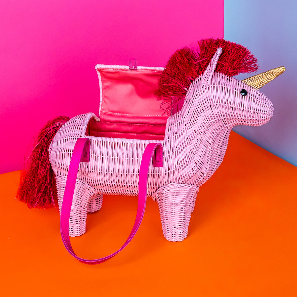 Vienna pink unicorn handbag pink unicorn purse features a red mane and sits in a colourful room.