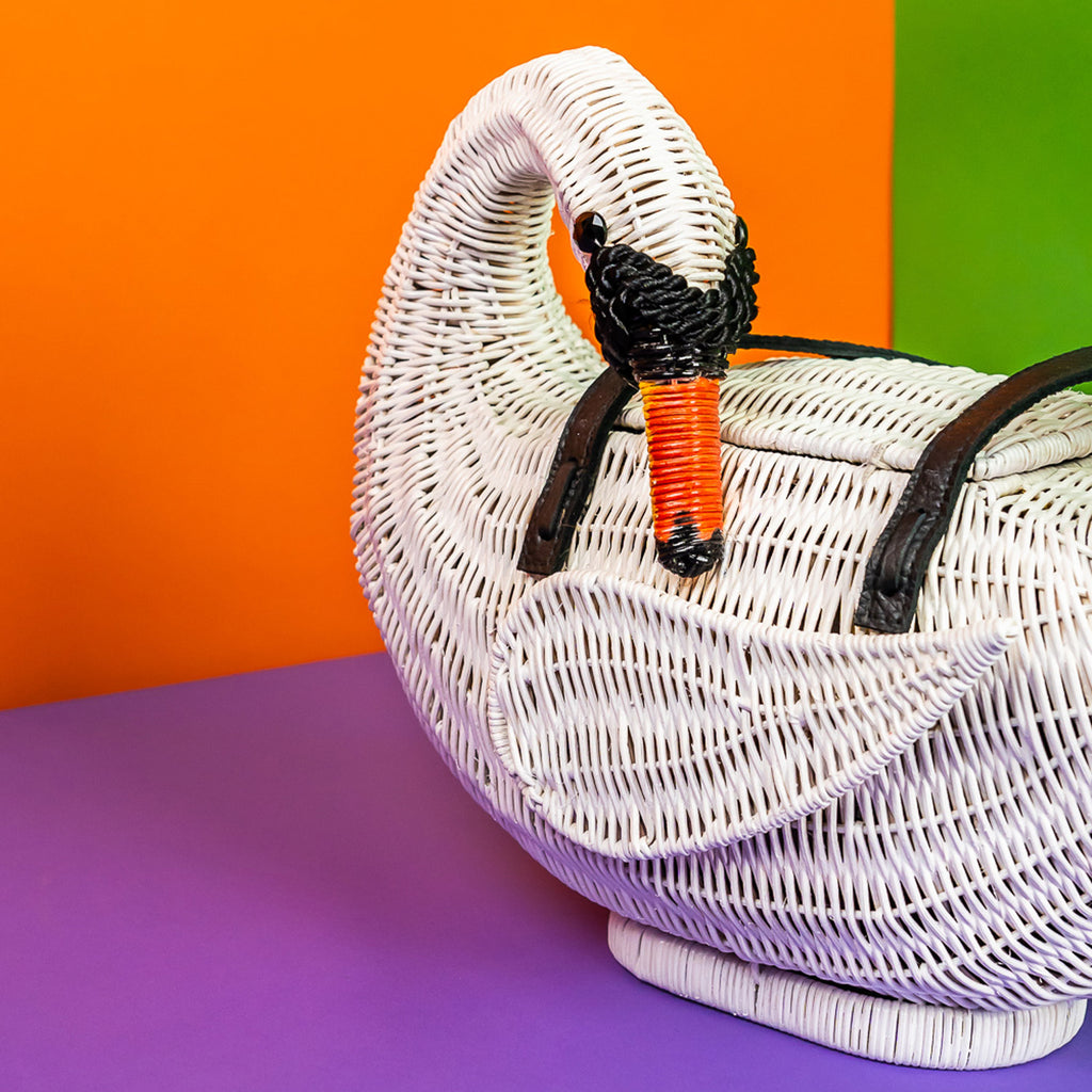 Wicker darling swan shaped bag wicker handbag sits in a colourful background.