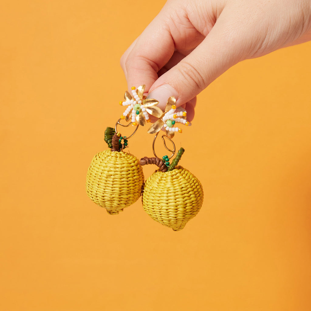 wicker darling hand woven citrus stud earrings in lemon variation in a colourful background