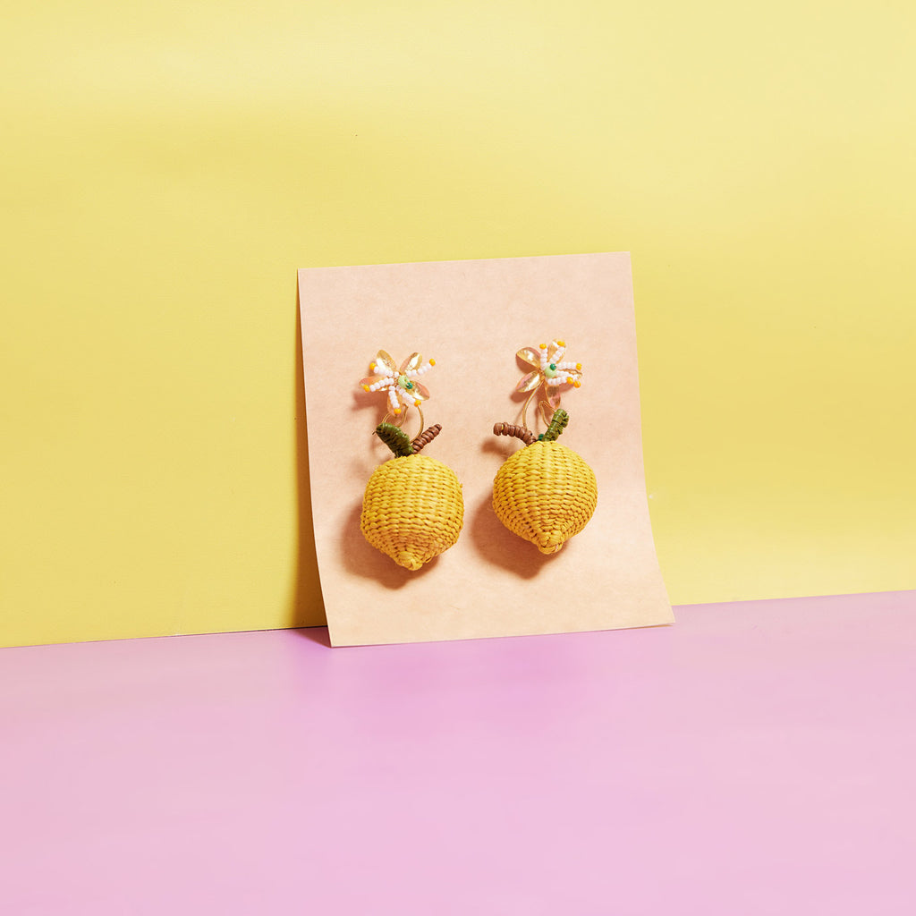 wicker darling hand woven citrus stud earrings in lemon variation in a colourful background