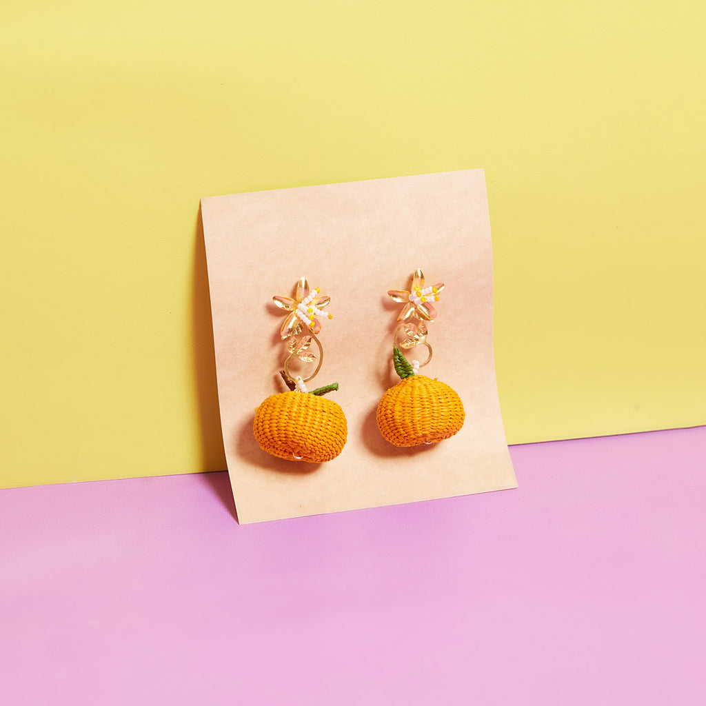 wicker darling hand woven citrus stud earrings in orange variation in a colourful background