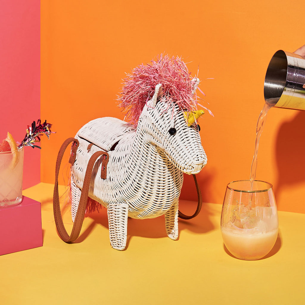 Wicker Darling Viv the unicorn shaped handbag unicorn purse sits in a colourful background